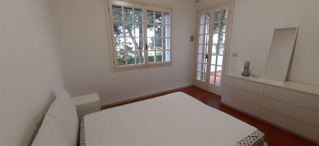 Camera da letto con letto matrimoniale, armadio e finestra che affaccia su un giardino.