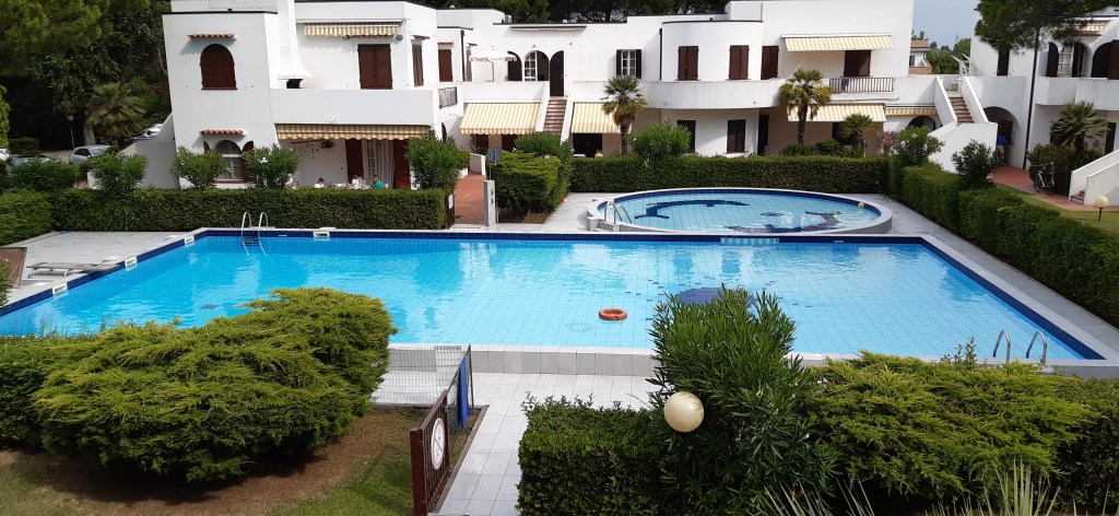 View of two swimming pools surrounded by greenery in the 'Alla Vigna' residence, located near Piazza Nember.