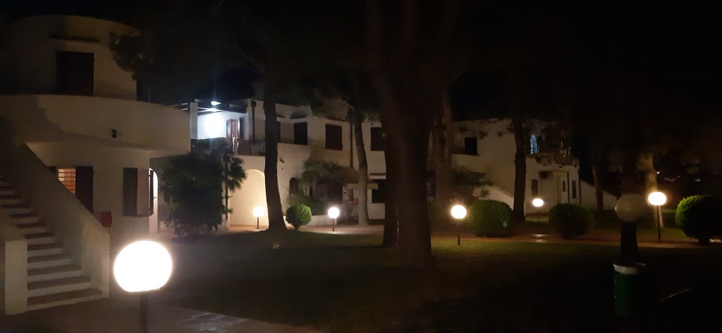Night view of a charming villa complex within the 'Alla Vigna' residence, featuring illuminated pathways and landscaped greenery.